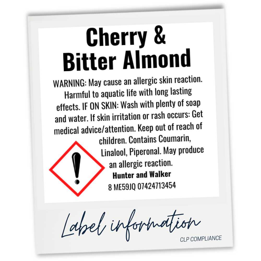 A square product label card with a white background and black text reading 'Cherry & Bitter Almond,' plus warning information, a red hazard symbol, and 'Label information' at the bottom. The card is photographed against a light gray background.
