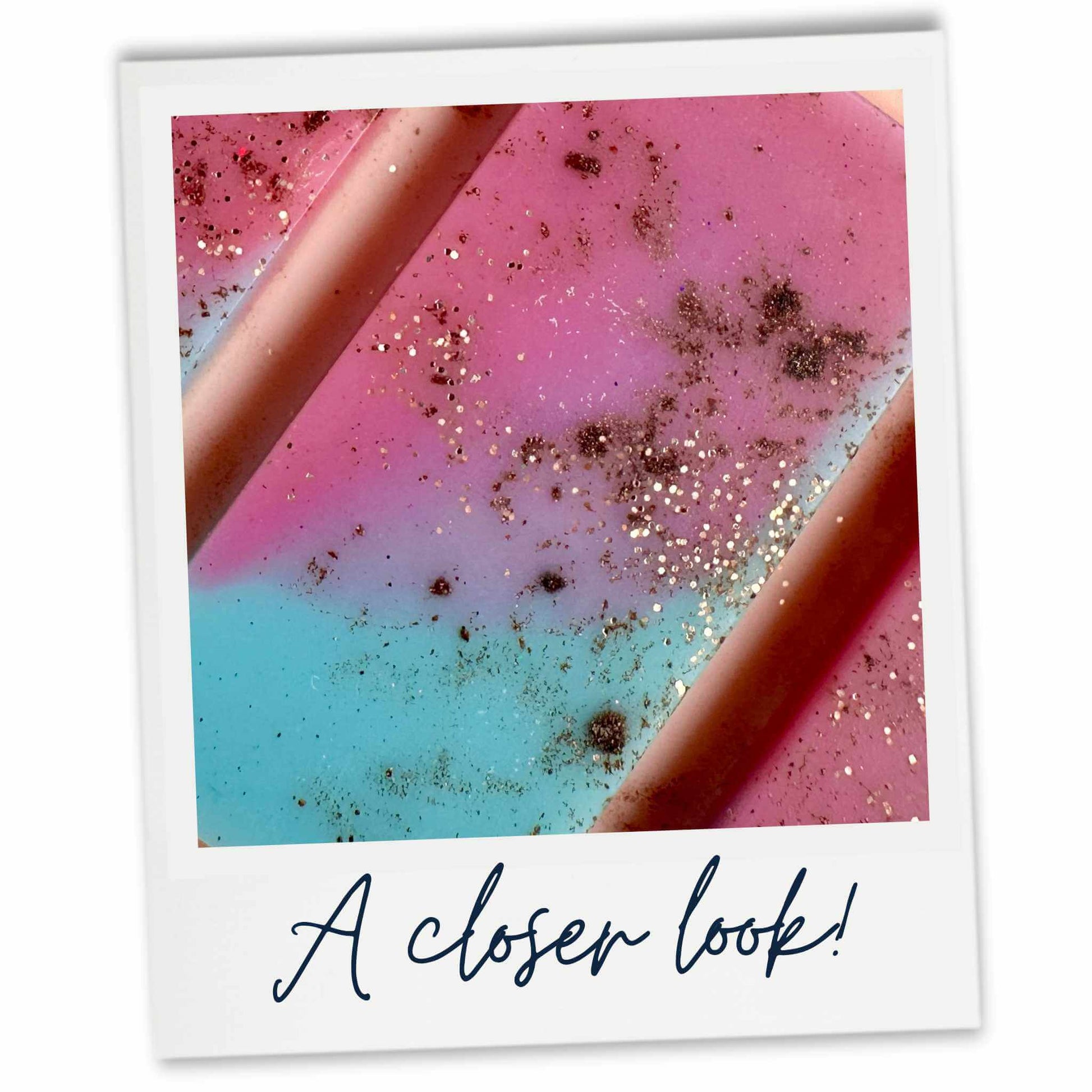 Close-up of a pink and blue wax melt with glitter, labeled 'A closer look!'.