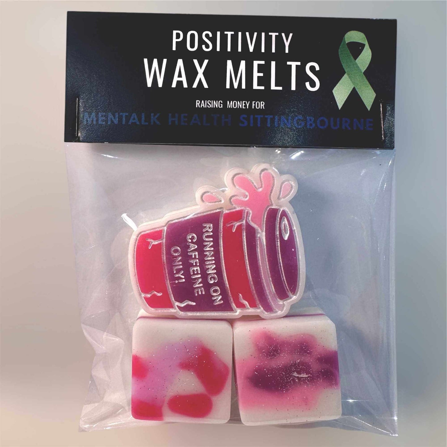 Positivity wax melts set with a pink, purple and white coffee cup design, featuring a green ribbon on a black background.