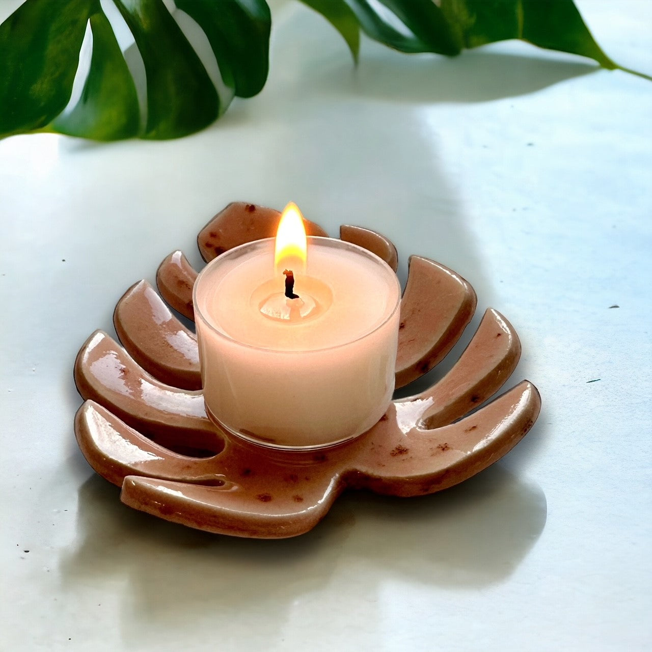 Pink Monstera leaf tealight holder with a lit candle life style image