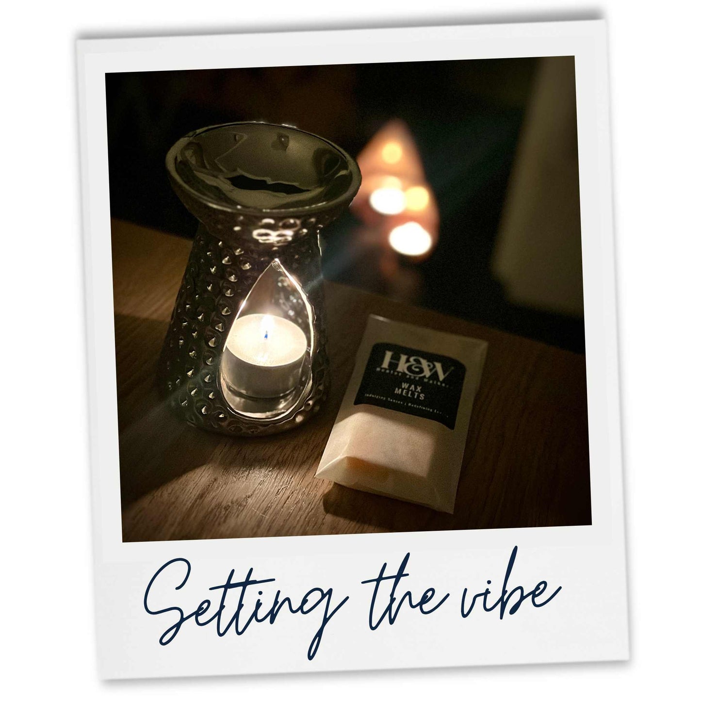 Candlelit scene with a wax melt and chrome wax melter on a wooden surface, labelled 'Setting the vibe'.