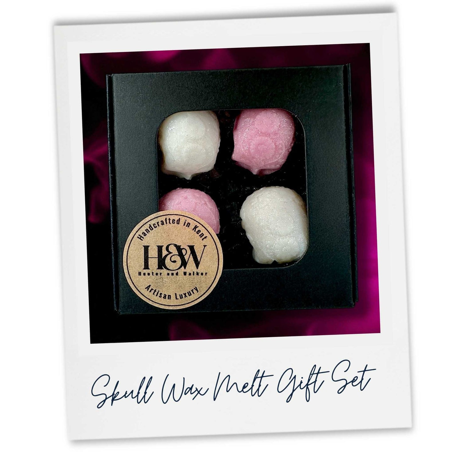 A Set of four pink and white skull wax melts in a closed black gift box.